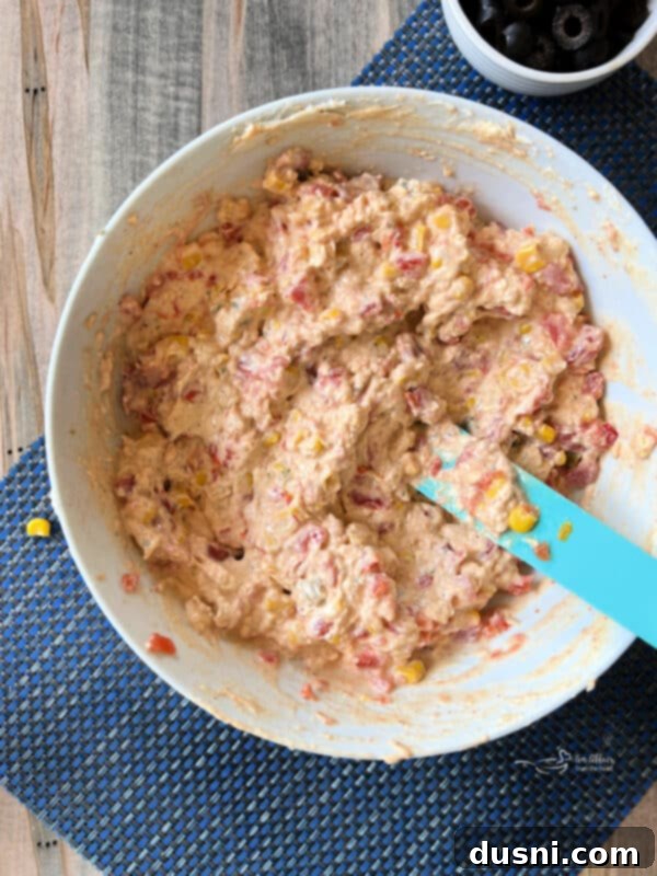 Easy 5 Ingredient Fiesta Corn Dip 7 Step two: Gently stirring Rotel tomatoes and Mexicorn into the cream cheese base.