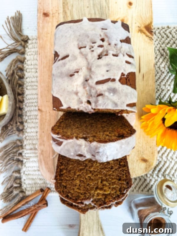 A perfectly baked loaf of pumpkin bread, sliced and presented on a wooden board, showcasing its moist texture and inviting autumn hue.