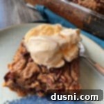 Pumpkin Dump Cake topped with vanilla ice cream on a cream colored plate