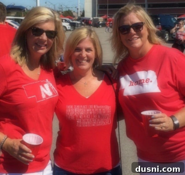Photo of three smiling women, Jill, Rhonda, and the author, at a Husker game.