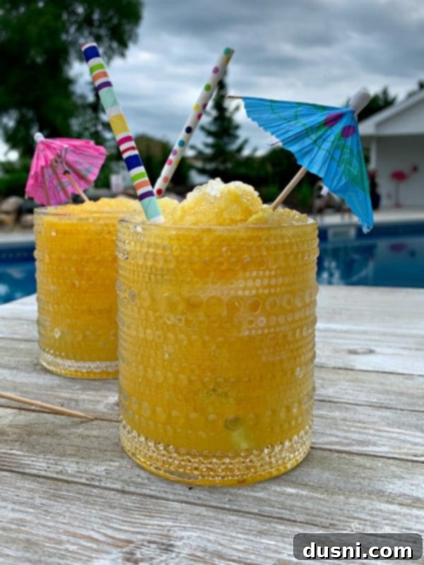 Close-up of a glass of frozen vodka slush with an umbrella, lemon slice, and straw.
