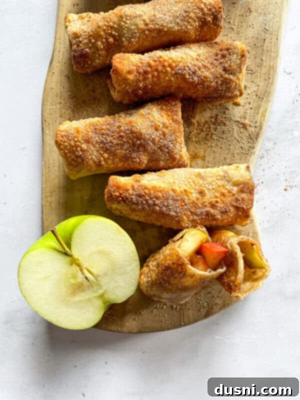 Air Fried Apple Pie Egg Rolls 2 Golden brown Air Fryer Apple Pie Egg Rolls with powdered sugar and caramel drizzle