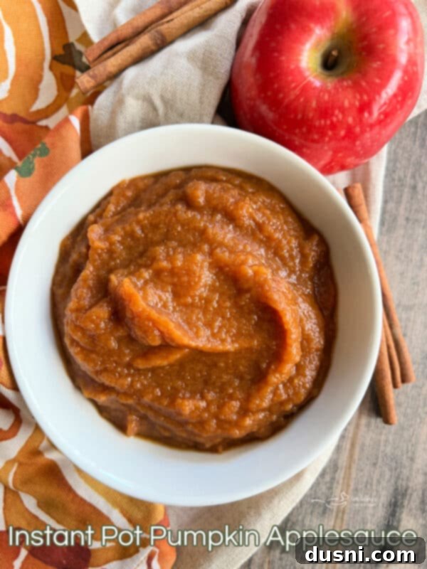 A large serving of Instant Pot Pumpkin Applesauce in a glass bowl, with a small individual bowl next to it.