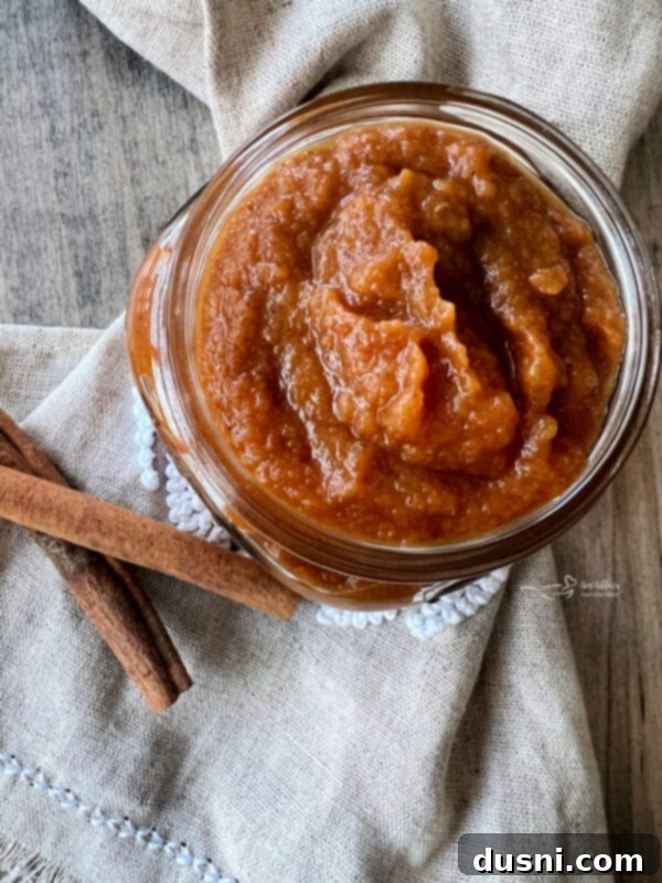 A bowl of fresh, peeled, and chopped apples next to a can of pumpkin puree, apple juice, and pumpkin pie spice.