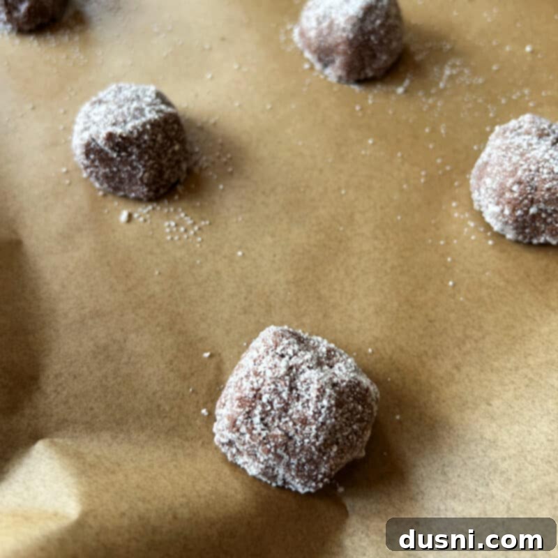 Cookie dough balls rolled in vanilla sugar on a baking sheet