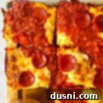 Homemade Detroit Style Pizza Perfection 21 Close up of Detroit style pizza on a wood board, emphasizing the crispy edges.