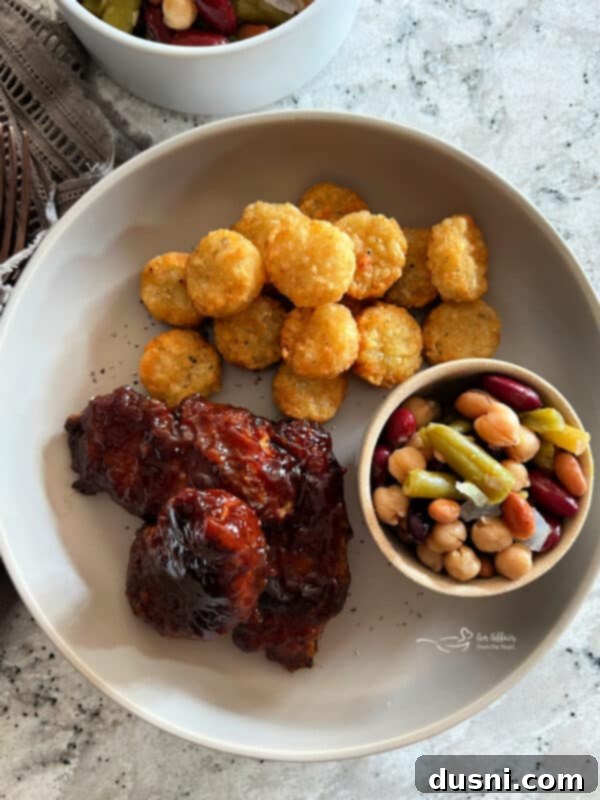 Completed plate with Air Fryer BBQ Chicken Tenders, tater tots and bean salad