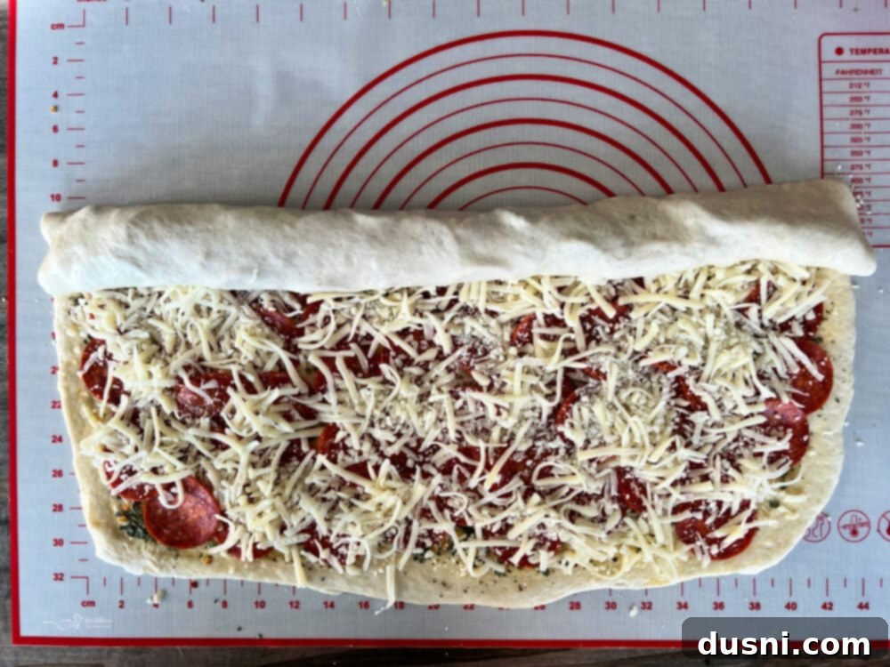Pizza dough layered with pepperoni slices, mozzarella cheese, and herbs, leaving a border around the edges.