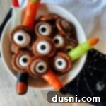 rolo pretzel eyeballs and plastic witches fingers in a white serving bowl.