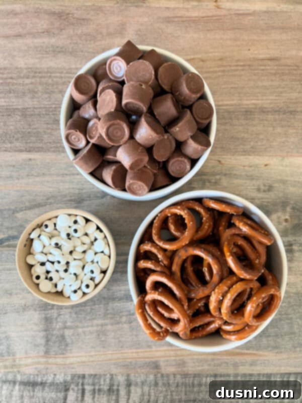 A close-up shot of several Rolo Pretzel Eyeballs arranged on a white marble surface, highlighting the detail of the candy eyeballs and the melted Rolo caramel.