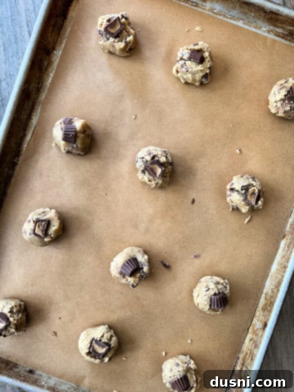Ultimate Reese's Peanut Butter Cookies 8 Another angle of cookie dough balls on a baking sheet, with Reese's minis pressed into each.