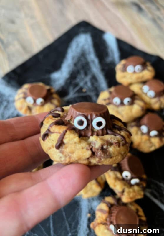 Piping chocolate legs onto a Reese's Peanut Butter Cup Spider Cookie
