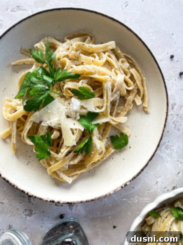 A serving of Instant Pot Fettuccine Alfredo in a bowl, garnished with herbs.