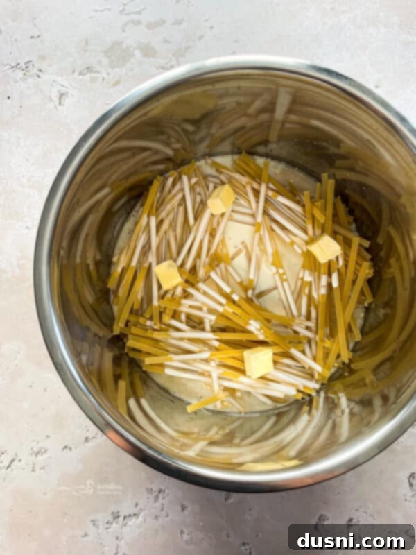 Layering fettuccine noodles in a crisscross pattern in the Instant Pot.