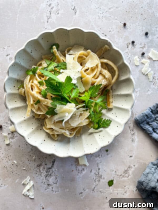 Finished Instant Pot Fettuccine Alfredo served in a white bowl with fresh parsley.