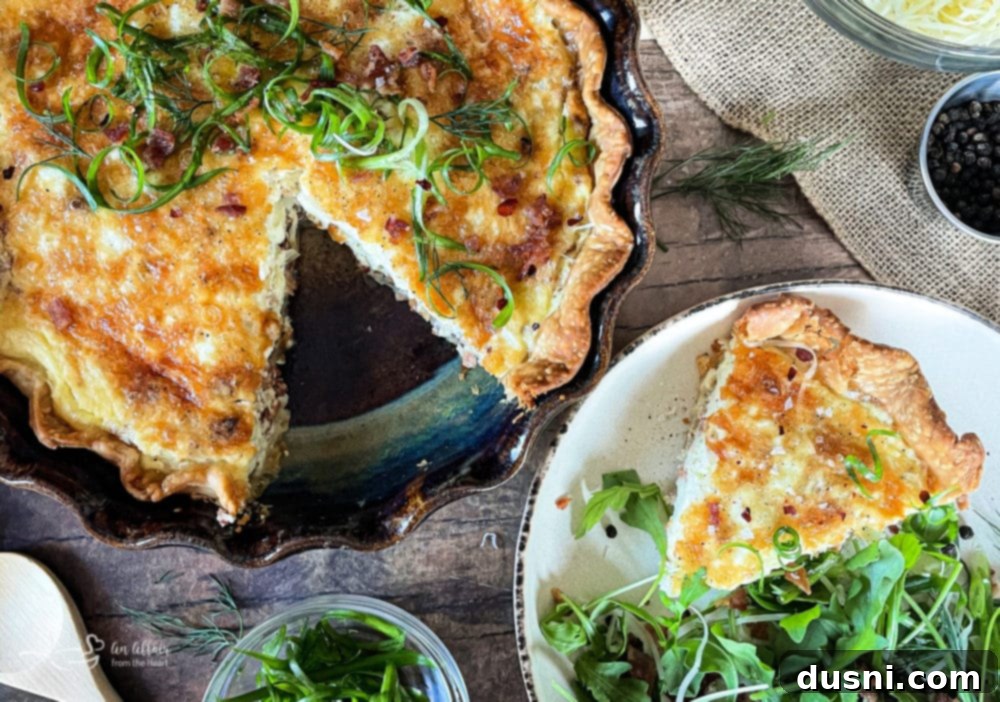 Overhead view of a cooked Bacon and Swiss Quiche in a pie dish with a spatula ready to serve