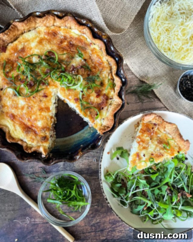 A slice of Bacon and Swiss Quiche on a plate, garnished with fresh herbs