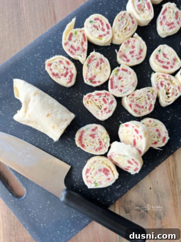 A chilled Reuben Style Tortilla Roll-Up, partially unwrapped, showing the firm texture before slicing.