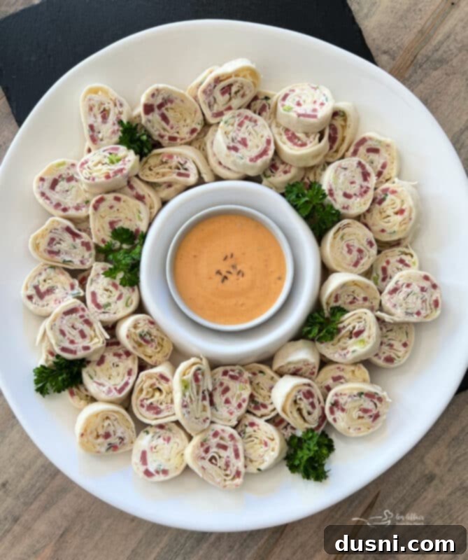 Close-up of freshly sliced Reuben Style Tortilla Roll-Ups on a white plate, showing the spiral layers of filling.