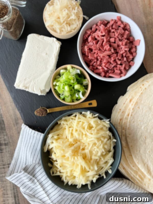 Ingredients for Reuben Style Tortilla Roll-Ups laid out on a table, including tortillas, cream cheese, corned beef, Swiss cheese, and Frank's Kraut.