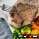 Homemade Bob Evans Style Pot Roast 18 close up of copycat Bob Evans pot roast sliced with a fork in one piece on a cream colored scalloped plate.