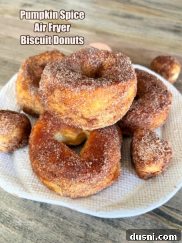 Golden Air Fryer Pumpkin Spice Biscuit Donuts 16 Hero shot of a plate of Pumpkin Spice Air Fryer Biscuit Donuts with fall decor