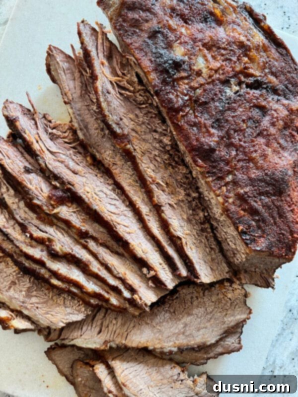 Texas Heat Smoked Brisket 12 Sliced spicy beef brisket served on a cutting board, against the grain.