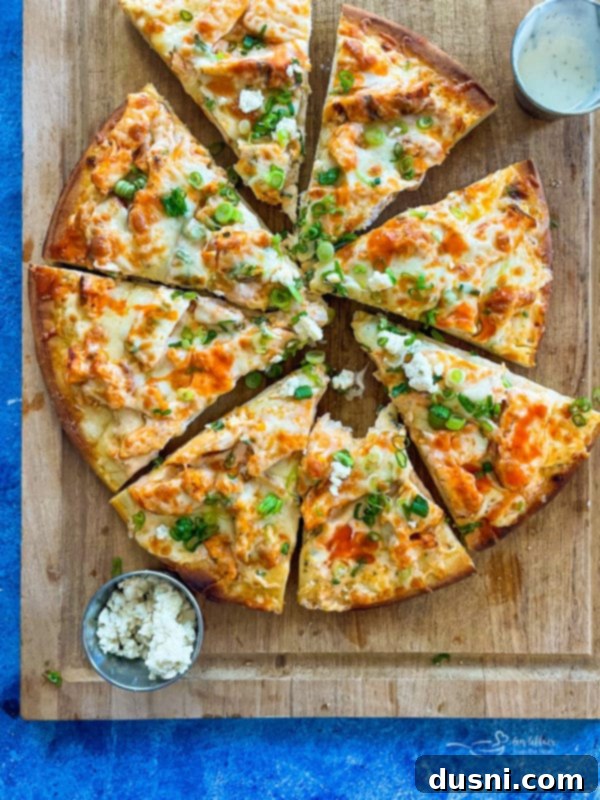 A sliced buffalo chicken pizza on a wood platter