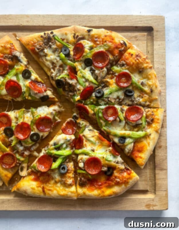 A Supreme Pizza baking inside a hot oven on a pizza stone.