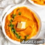 Instant Pot Sweet Potato Mash topped with parsley and butter in a white serving bowl