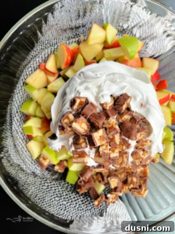Decadent Snickers Apple Salad 10 Step three: Combining diced apples, chopped Snickers, and Cool Whip in a bowl