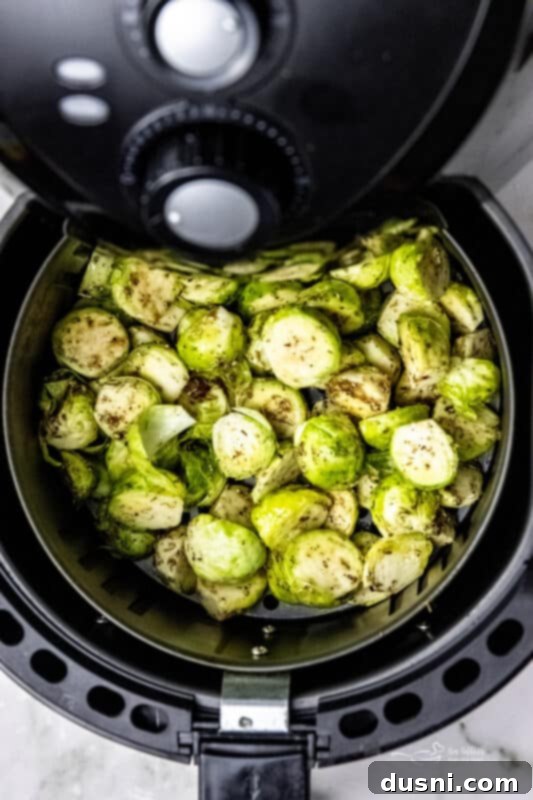 Two hands reaching for a bowl of freshly cooked Air Fryer Brussels Sprouts.