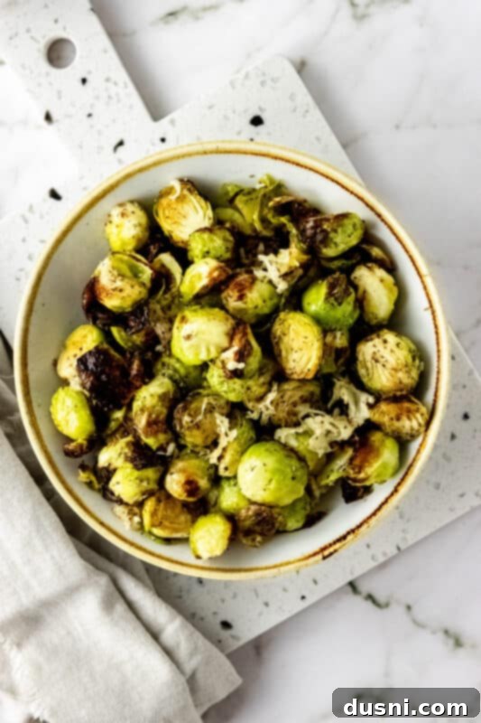 A bowl of air-fried Brussels sprouts topped with parmesan cheese, ready to be served.