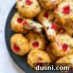 Cherry wink cookies stacked on a blue serving plate with one broken in half.