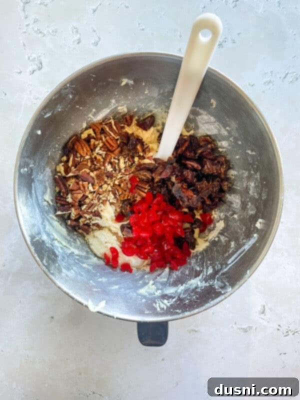 Adding pecans, dates, and chopped cherries to the cookie dough.