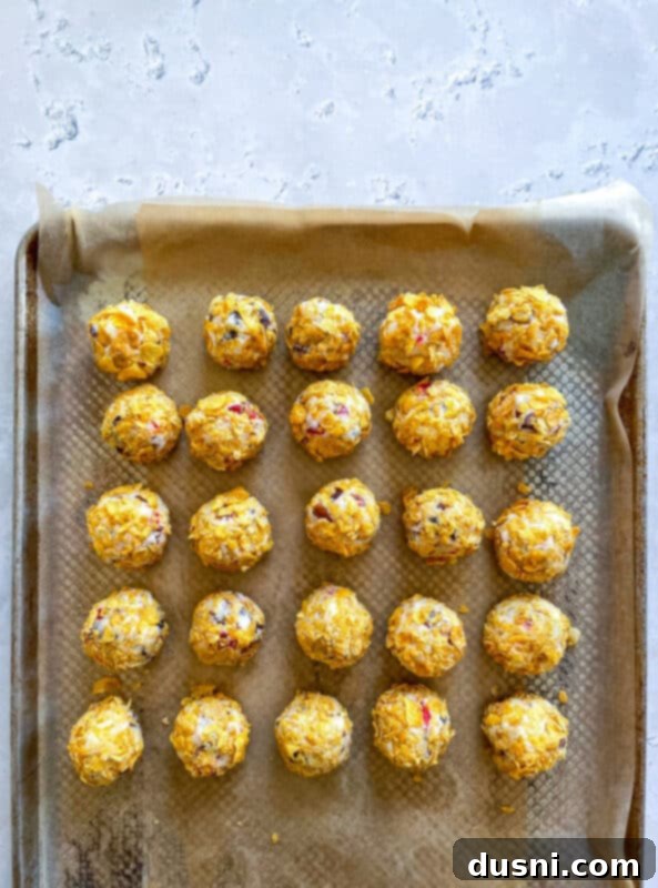 Cookie dough balls being rolled in crushed cornflakes.