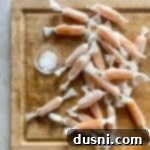 Wrapped homemade caramels on a wood cutting board.