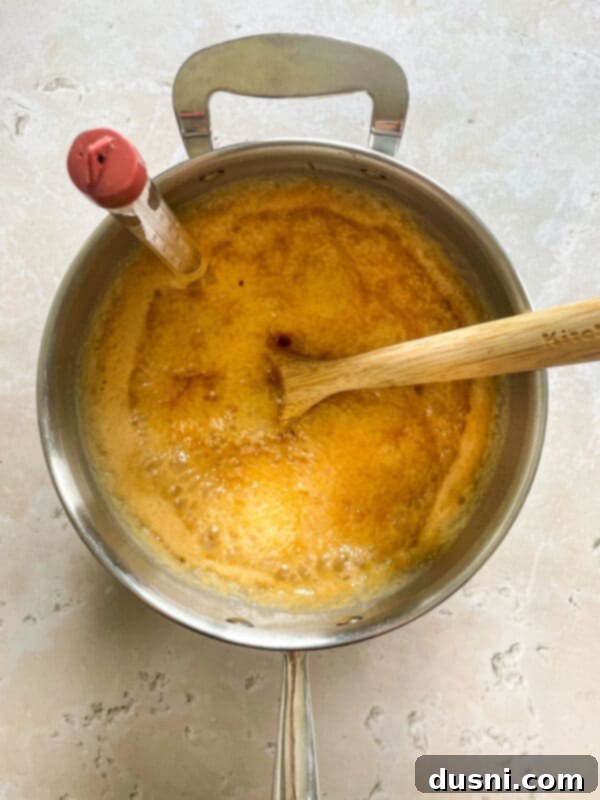 Ingredients for homemade caramels being stirred in a saucepan on the stove.