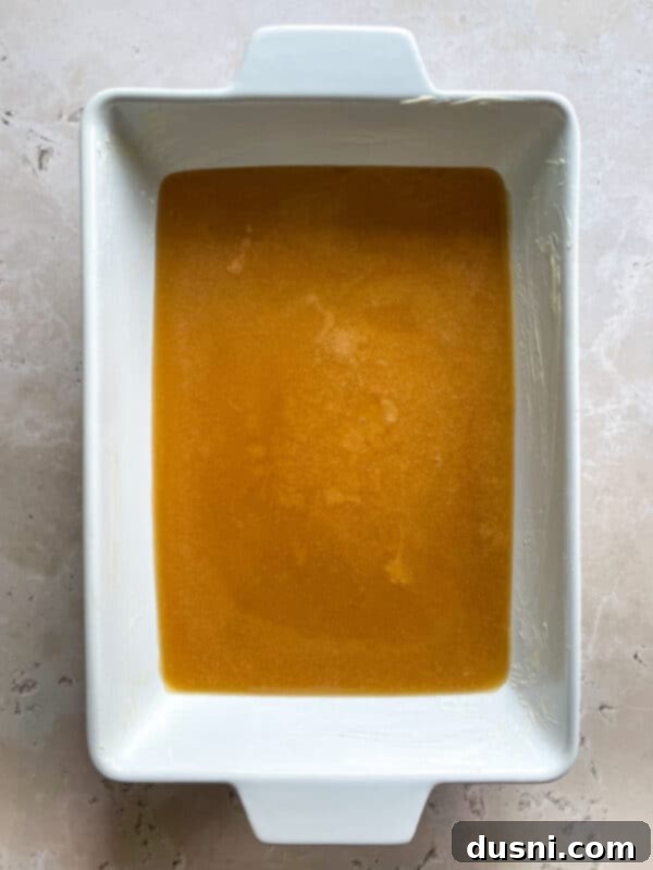 Vanilla extract being stirred into the hot caramel mixture in a saucepan.