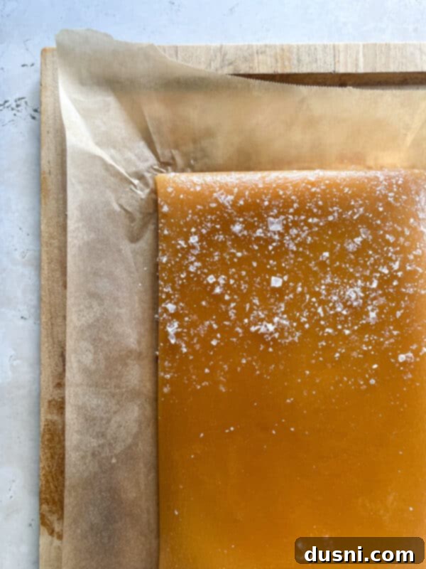 Hot caramel mixture being poured into a parchment-lined baking dish.