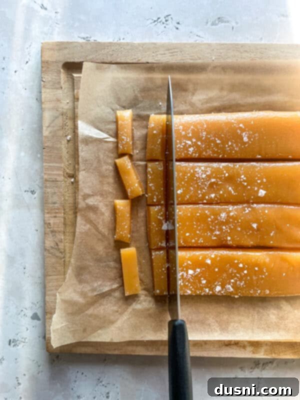 Flaky sea salt being sprinkled over freshly poured caramel in a baking dish.