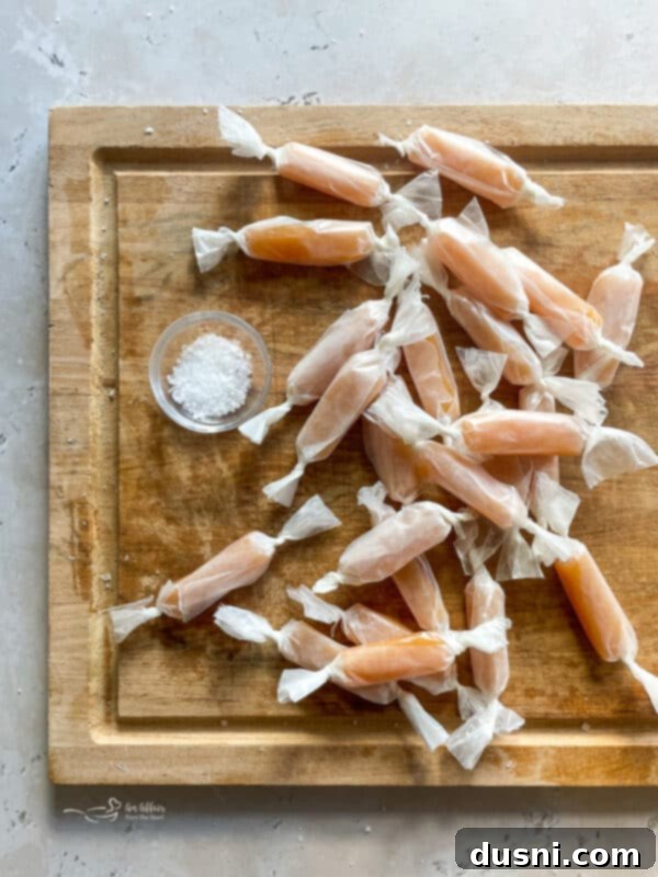 Cooled caramel slab being cut into individual pieces with a sharp knife.