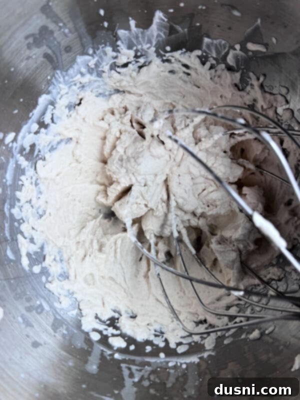 Stiff peaks formed after whipping cream, sugar, and vanilla, showing the perfect texture before adding sour cream.