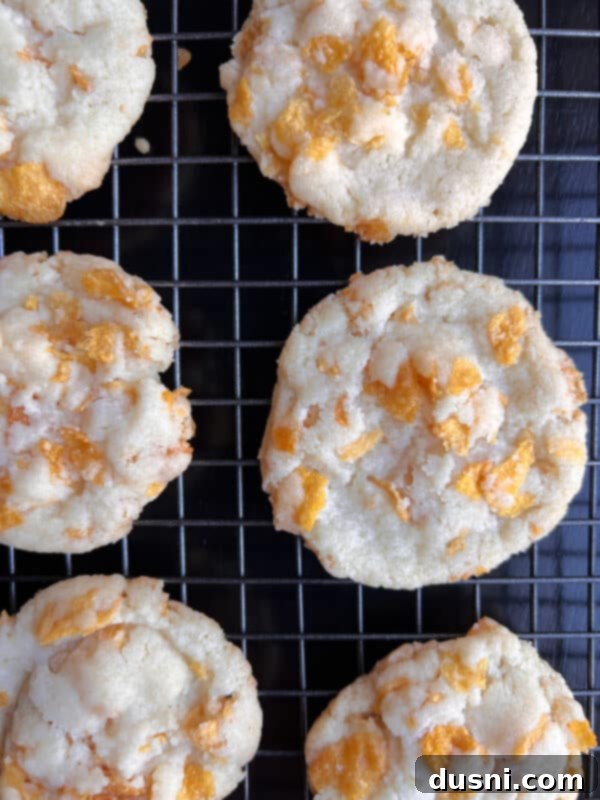 Freshly baked Cornflake Cookies on a parchment-lined baking sheet, golden brown at the edges.