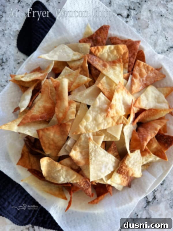 Crispy Air Fryer Wonton Chips 9 A large bowl of crispy air fryer wonton chips, piled high and ready for serving, on a wooden table.