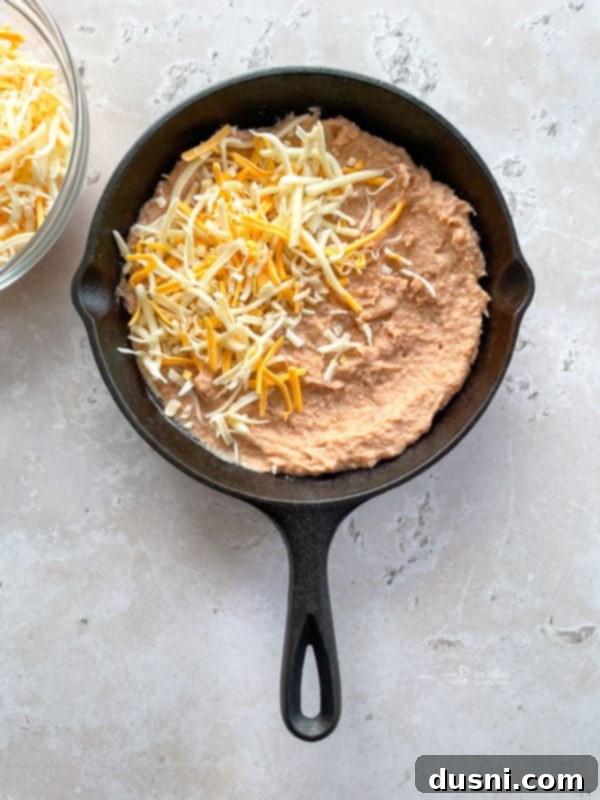 adding cheese on top of the bean dip