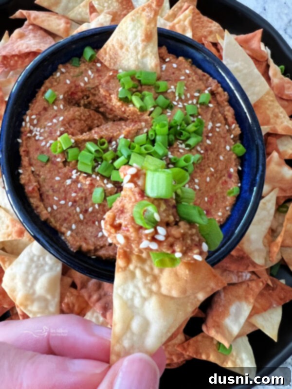 Close-up of Asian Bean Dip in a blue bowl, garnished with green onions and sesame seeds