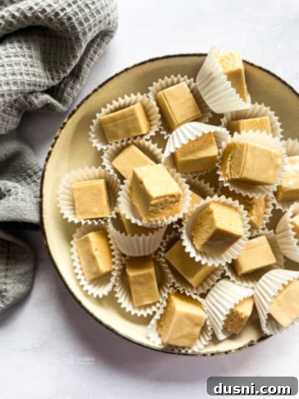 Decadent Peanut Butter Fudge 2 Stacked squares of creamy peanut butter fudge on a serving plate.