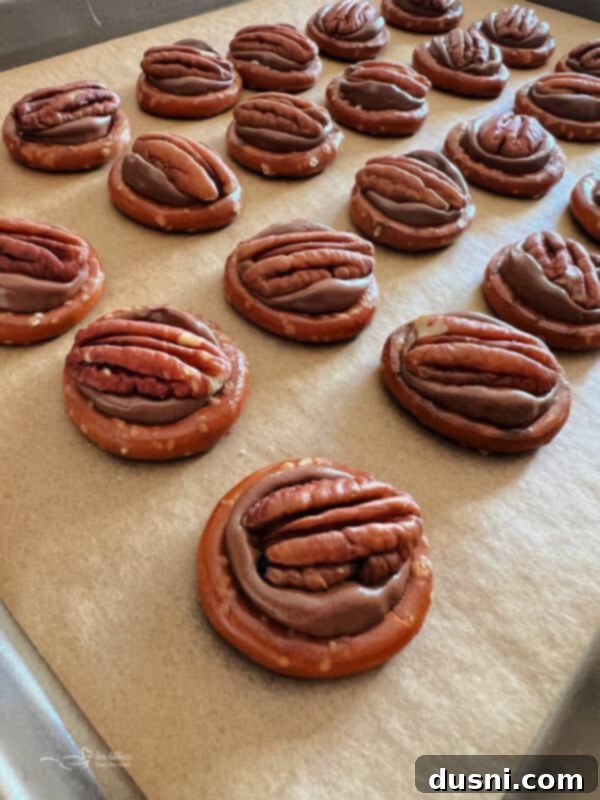Rolo candies placed on pretzels on a baking sheet, ready for the oven