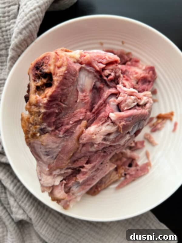 Instant Pot Grandmas Comforting Ham and Bean Soup 6 A ham bone with some meat left on it, on a white plate